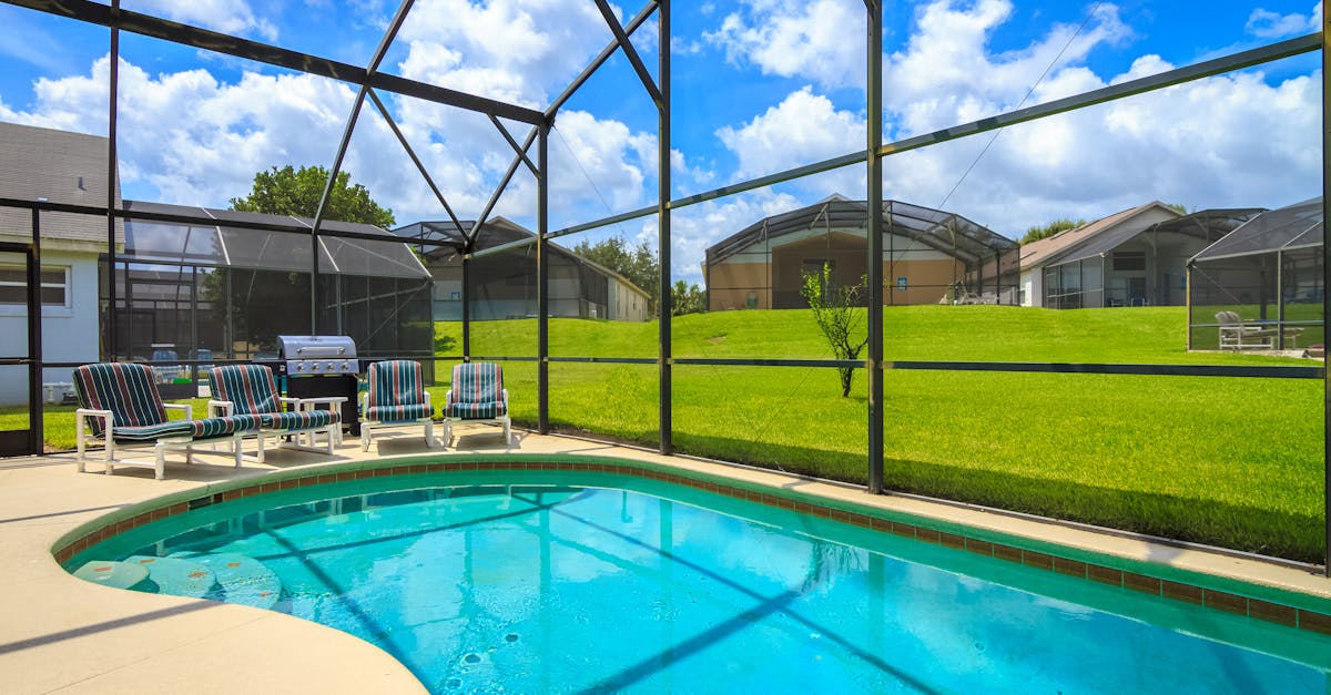 A sunny outdoor enclosed pool at a Florida villa with lounge chairs and a grill, perfect for relaxation.