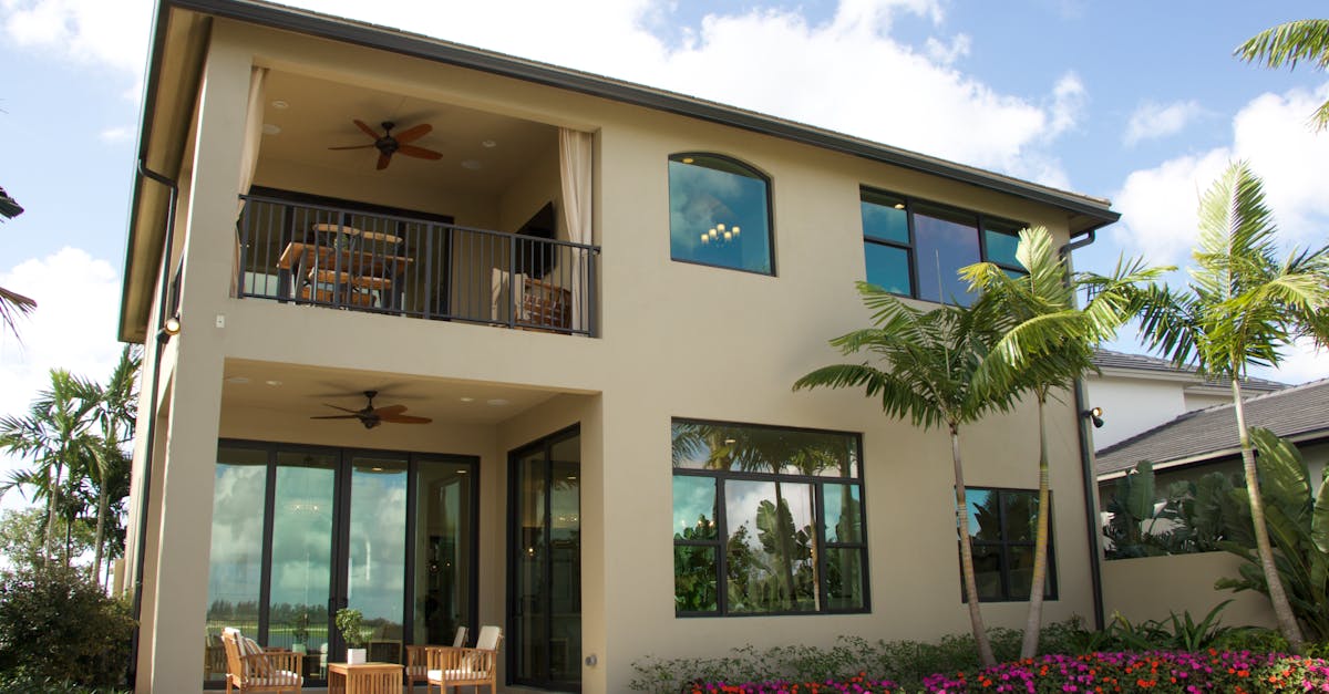 A modern two-story home in Florida with a balcony, patio, and lush garden.