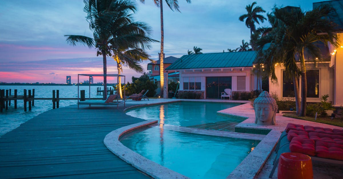 Experience a serene tropical villa with a poolside view during sunset in Miami Beach, featuring palm trees and tranquil waters.